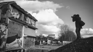 Eine Person steht auf einem Hügel und fotografiert ein mit Graffiti bedecktes Gebäude
